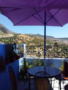 a purple umbrella on a balcony with a table and chairs at Dar Lbakal in Chefchaouen