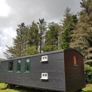 una piccola casa nera con finestre e alberi di Annascaul Train Carriage suit couple and 2 children ad Anascaul