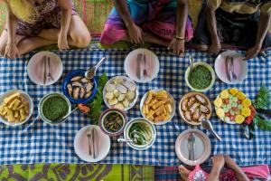 un grupo de personas sentadas en una mesa con comida en Namosi Eco Retreat, en Navunikambi