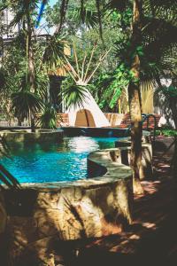 a swimming pool with a bench and palm trees at Bufo Alvarius in Tulum