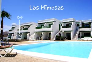 un hotel con piscina frente a un edificio en Magmamia en Puerto del Carmen