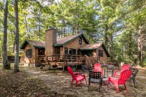 a log cabin with red chairs in front of it at Beach House in Manitowish Waters