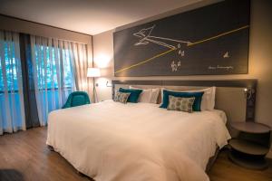 a hotel room with a large white bed with a clock on the wall at Royal Tulip Brasília Alvorada in Brasilia