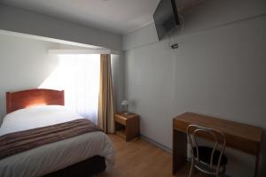 a bedroom with a bed and a desk and a television at Hotel Quitor in Calama