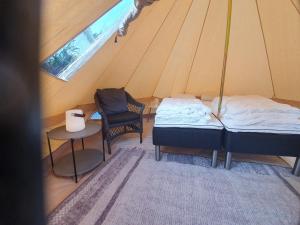 a room with two beds and a chair in a tent at Dalsøren Camping og hytter in Luster