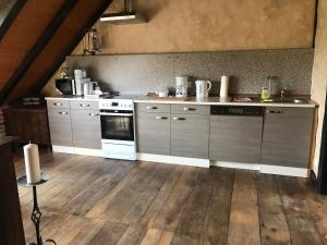 cocina con electrodomésticos de acero inoxidable y suelo de madera en Fewo TURMZIMMER im Rittergut Leppersdorf bei Dresden, en Leppersdorf