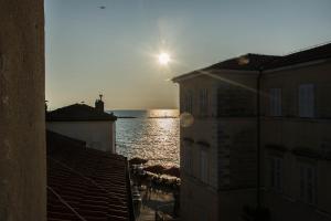 a sun setting over the water between two buildings at Oli mare in Poreč