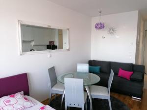 een woonkamer met een bank en een glazen tafel bij Lanterna Apartman - free parking in Zagreb