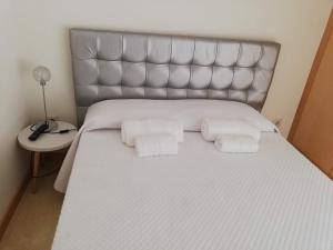 a large bed with white sheets and pillows at Apartamento Praia do Relógio in Figueira da Foz
