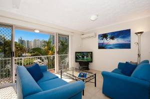 a living room with two blue couches and a tv at Champelli Palms Apartments in Gold Coast