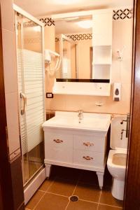 a bathroom with a sink and a toilet and a mirror at Guest House Stena in Ersekë