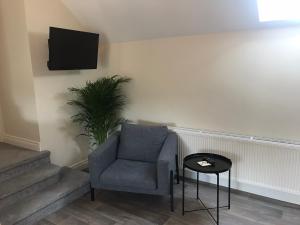 a living room with a chair and a tv on the wall at Bush House Accommodation - The Distillery in Bushmills