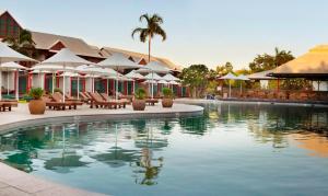 einen Pool mit Stühlen und Sonnenschirmen in einem Resort in der Unterkunft Cable Beach Club Resort & Spa in Broome
