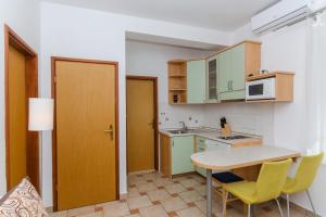 a small kitchen with a table and yellow chairs at Apartments Marjan in Brna