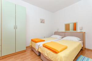 two beds in a bedroom with white walls and wood floors at Apartments Marjan in Brna