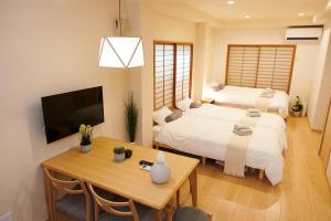 a bedroom with two beds and a table and a tv at Ueno Residence Hotel Matsumoto in Tokyo