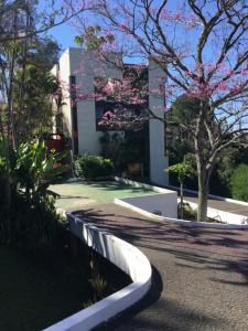 a building with a tree with pink flowers on it at Pitaya Suítes in Cunha