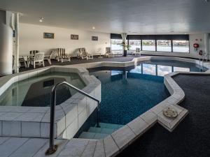 a pool in a hotel with chairs and tables at Lakes Hotel in Adelaide