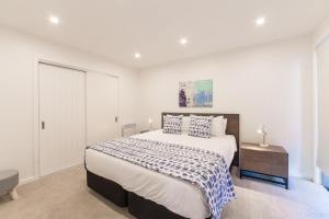 a white bedroom with a large bed and a table at Executive Living in Bluewater - 3 Bedroom Apartment in Queenstown