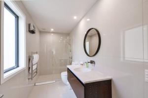 a white bathroom with a sink and a mirror at Executive Living in Bluewater - 3 Bedroom Apartment in Queenstown +12 photos