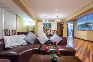 sala de estar con sofá de cuero marrón y mesa en Espacioso confortable apartamento familia, en Cusco