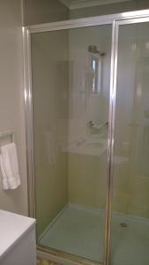 een badkamer met een glazen douche en een wastafel bij Canberra Carotel Motel in Canberra