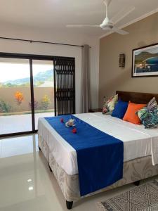 ein Schlafzimmer mit einem großen Bett mit einer blauen Decke in der Unterkunft Whispering Palms in Bel Ombre