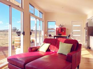 a living room with a red couch and windows at Pieter van Gent Winery & Vineyard in Eurunderee