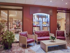 un vestíbulo de tienda con sillas púrpuras y una mesa en Mercure Limoges Centre, en Limoges