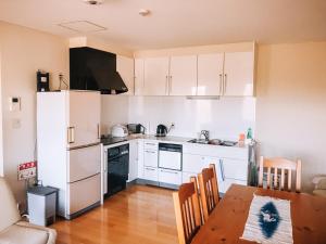 a kitchen with white cabinets and a wooden table with a dining room at Yotei Townhouse - 2 bedrooms with covered BBQ deck in Niseko
