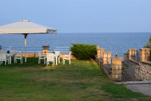 a table and chairs with an umbrella and the ocean at Alexandros Apartments & Αλέξανδρος Villas in Kalamaki Messinia