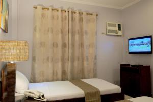 a small room with a bed and a television at Palazzo Pensionne in Cebu City