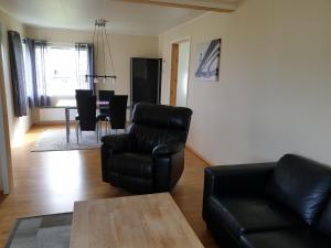 a living room with a black leather chair and a table at Søndre Berg gate 20 Apartement in Vardø