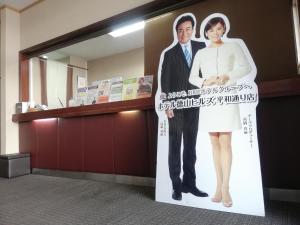 a poster of a man and a woman on a sign at Hotel Tokuyama Hills Heiwadoriten in Shunan