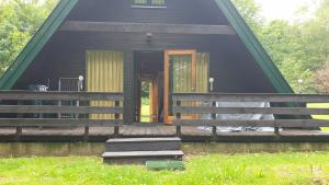 ein schwarzes Haus mit einer Veranda und einer Tür in der Unterkunft Ferienhaus Nr. 40 im Ferienpark am Twistesee in Bad Arolsen