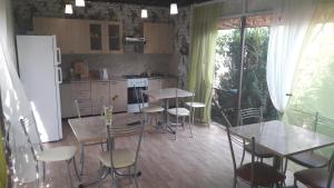 cocina con mesas, sillas y nevera en AdlerOk Guest House, en Adler
