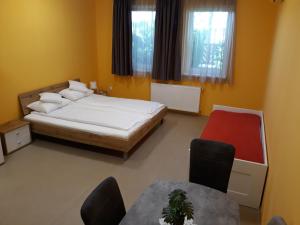 a bedroom with a bed and a table and chairs at Bella Vendégház Mórahalom in Mórahalom +5 photos