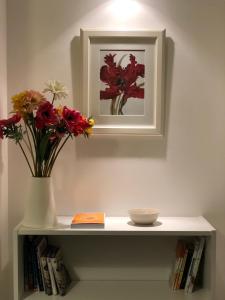 a shelf with a vase of flowers and a book at Great Central Apartment in Rome