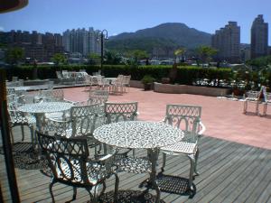 a patio with tables and chairs with a view of a city at Hotel RegaLees in Tamsui