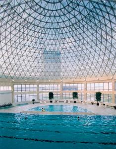 a large swimming pool in a building with a domed ceiling at Ramada Plaza Sino-Bay Shanghai in Fengxian