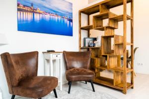 twee stoelen in een kamer met een boekenplank bij Centerapartments Tonhallenstraße in Düsseldorf