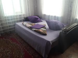 ProletarkaにあるU Iriny Guest Houseの紫色の枕と毛布付きのベッド