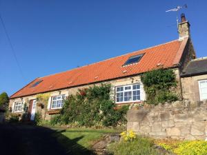 una casa antigua con techo naranja en Birdsong Cottage Bed and Breakfast en Chathill