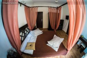 a bedroom with a bed with orange curtains at Residenza Dutzu-Boutique Hotel in Brăila