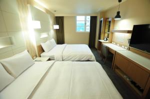 a hotel room with two beds and a flat screen tv at Kindness Hotel Hualien in Hualien City