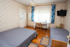 a bedroom with two beds and a desk and a window at Guest House ANA.k in Postojna