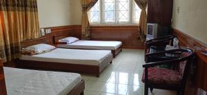 a room with three beds and a chair and a tv at Hue Railway Hotel in Hue