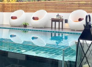 a pool with white chairs and a table next to a pool at Pai Cherkaew Boutique House in Pai