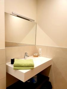 een wastafel met een spiegel en een groene handdoek bij Versigglhof in Appiano sulla Strada del Vino