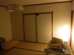 a room with a bed with a door and a lamp at Wholeearth Ryokan Hiroshima in Hiroshima